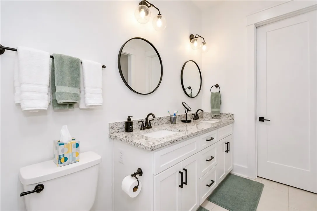 Double vanities with sleek hardware and granite counters elevate this elegant bathroom.