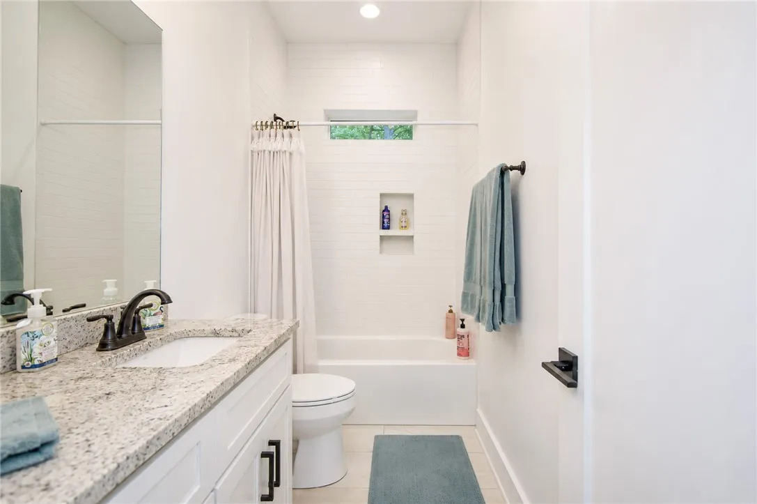 A well-lit bathroom features a vanity with granite counters and an integrated tub and shower.