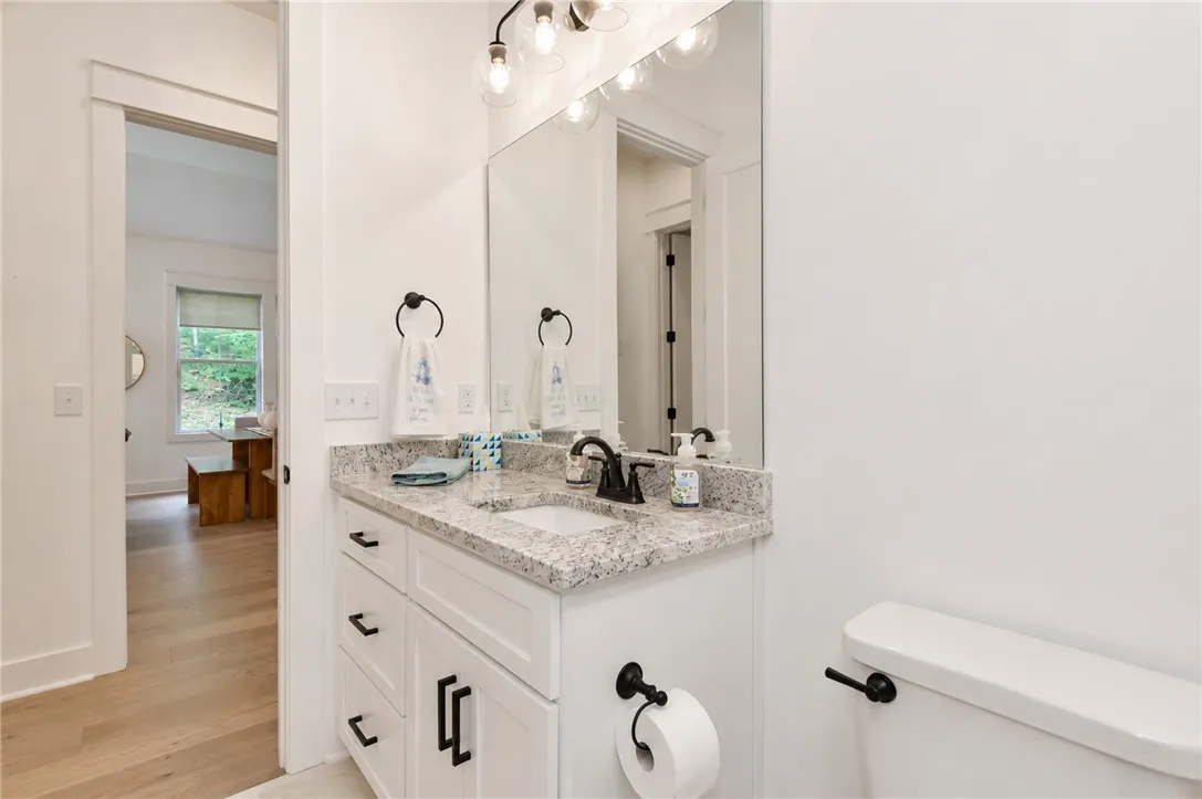 A well-appointed bathroom vanity features a granite countertop and contemporary fixtures, adjacent to a brightly lit space.