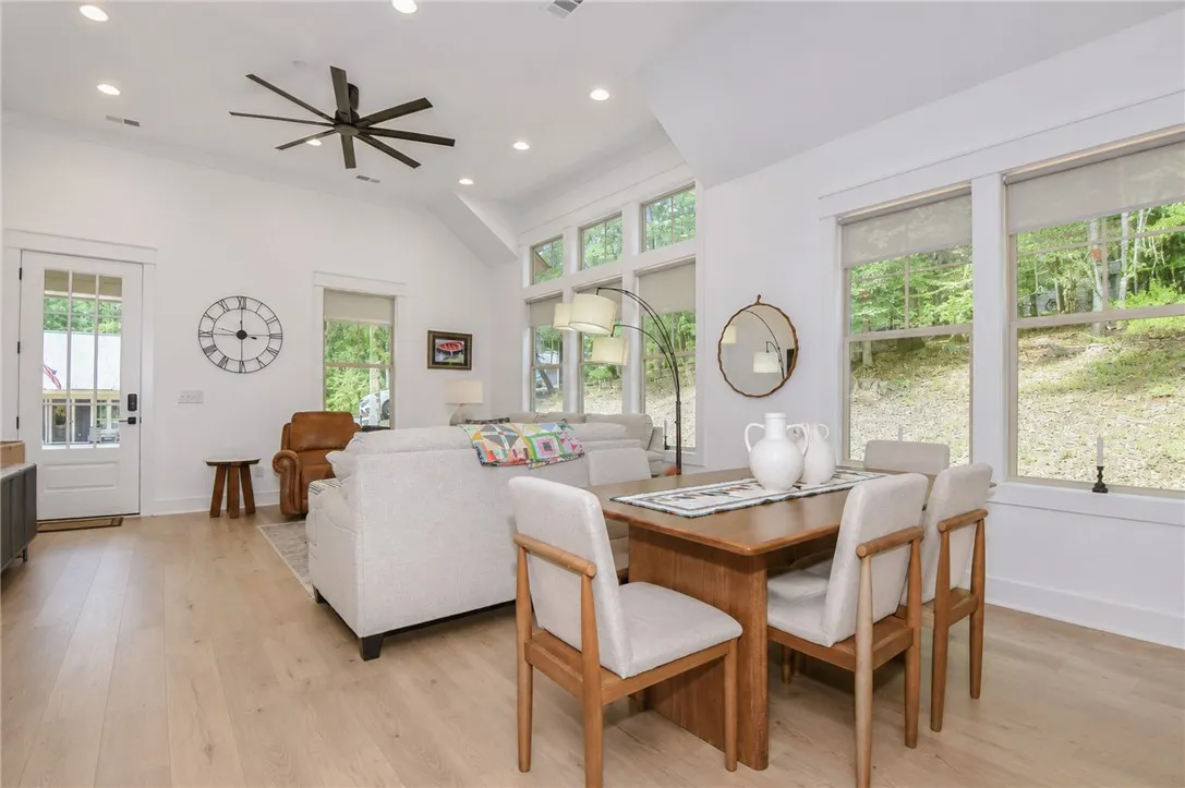 Natural light pours into this combined living and dining space, showcasing the rich wood flooring and vaulted ceilings.
