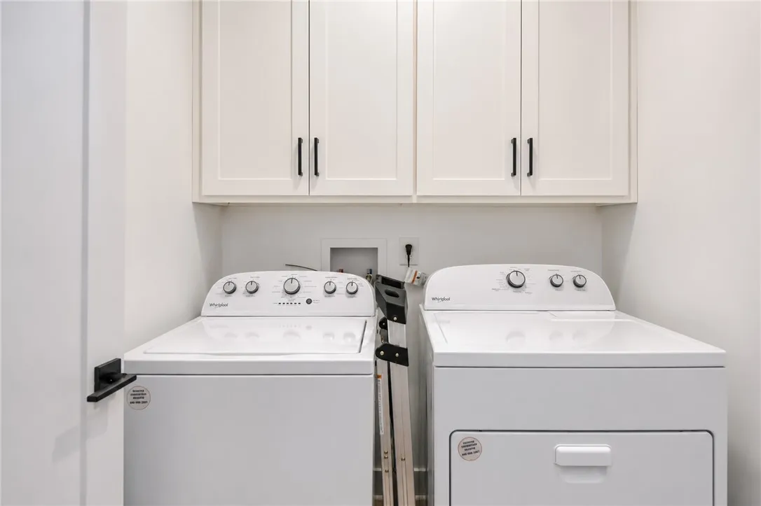 Functional laundry space featuring modern appliances and practical overhead storage.