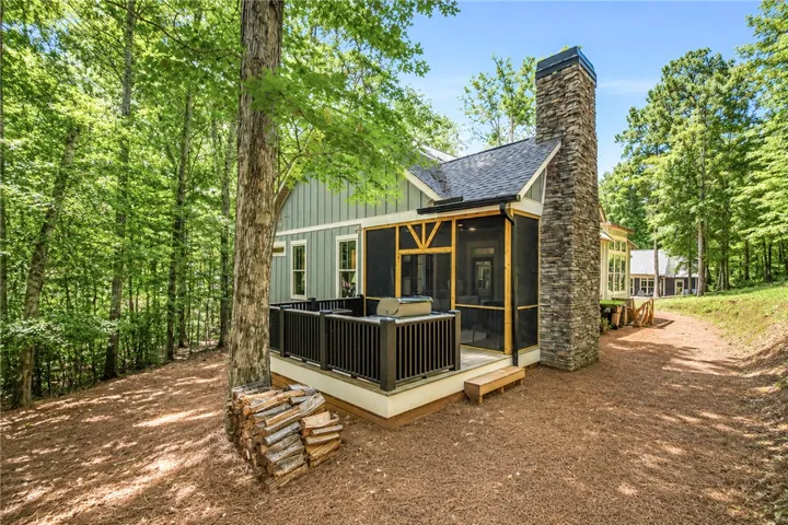 A tranquil woodside retreat features a screened porch and expansive outdoor deck.