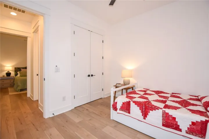 Blonde hardwood floors grace this naturally illuminated bedroom, complete with bright white walls.