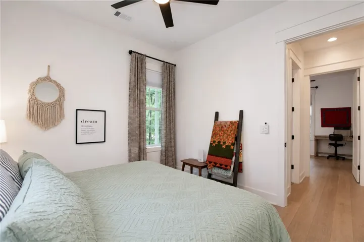 Well-lit sleeping quarters with bright white walls, hardwood flooring, and a large window overlooking natural surroundings.