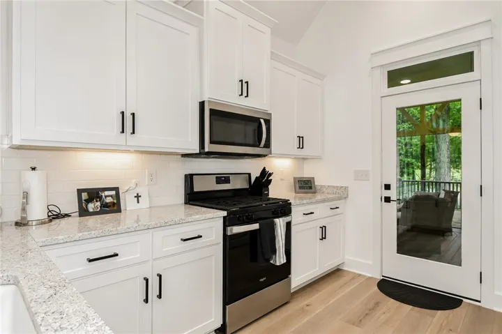 White cabinetry, light granite countertops, and light wood flooring define this kitchen's bright and modern aesthetic.
