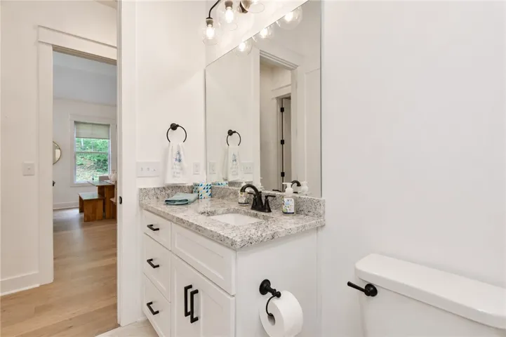 A well-appointed bathroom vanity features a granite countertop and contemporary fixtures, adjacent to a brightly lit space.