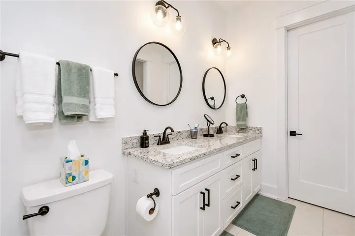 Double vanities with sleek hardware and granite counters elevate this elegant bathroom.
