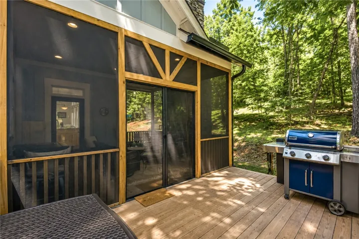 A spacious wooden deck extends from a screened-in porch, ideal for outdoor gatherings.