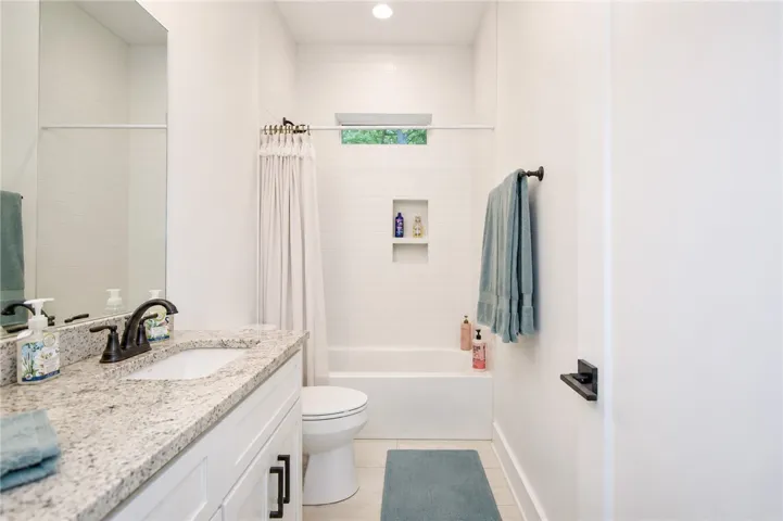 A well-lit bathroom features a vanity with granite counters and an integrated tub and shower.