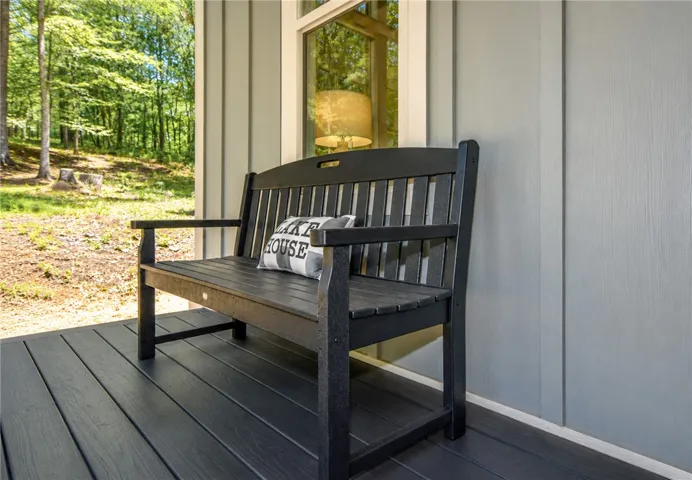 A welcoming front porch features durable decking and board-and-batten siding, nestled amidst a tranquil woodland setting.