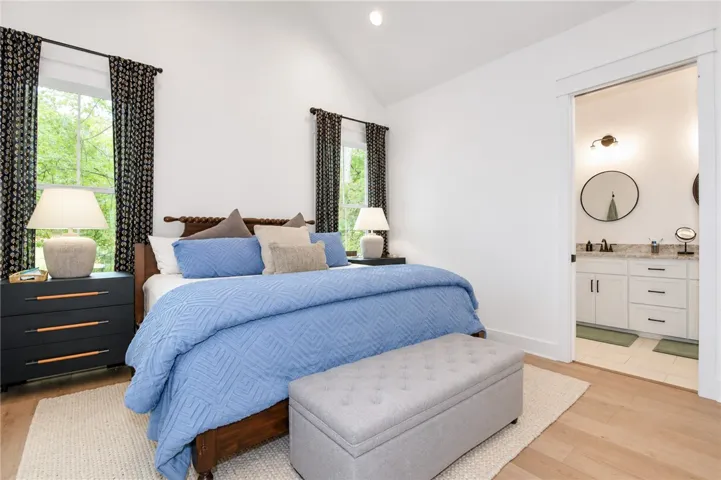 A tranquil primary bedroom with vaulted ceilings and abundant natural light from a large window.