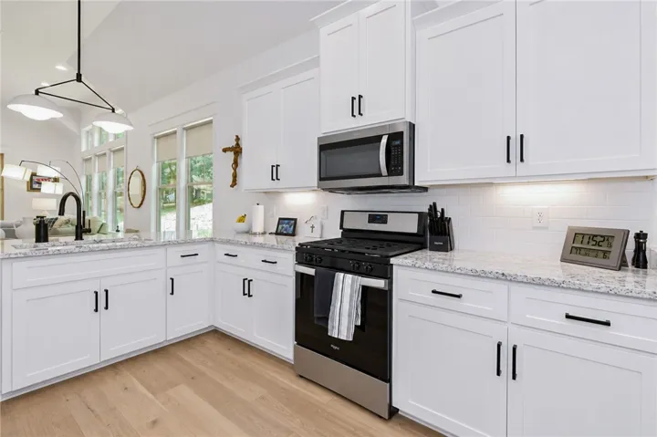 White cabinetry, light wood floors, and ample counter space create an inviting, open kitchen.
