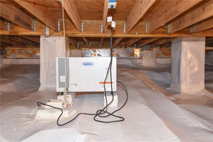 A well-maintained crawl space with visible beams and a dehumidifier system ensures optimal property conditions.