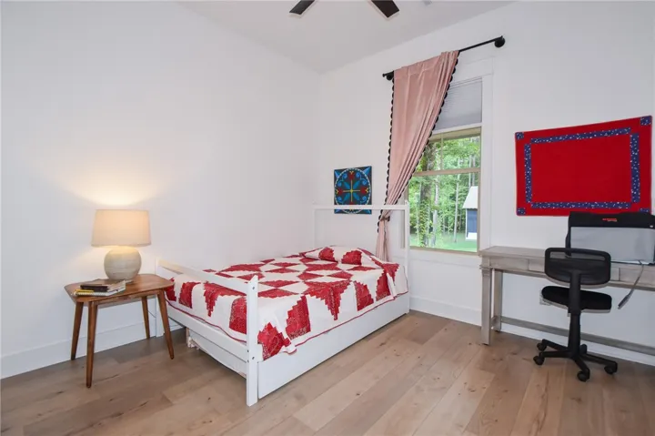 Hardwood floors and a sun-filled window create a comfortable and inviting bedroom retreat.