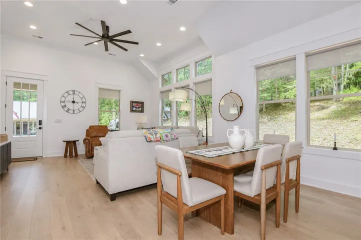 Natural light pours into this combined living and dining space, showcasing the rich wood flooring and vaulted ceilings.
