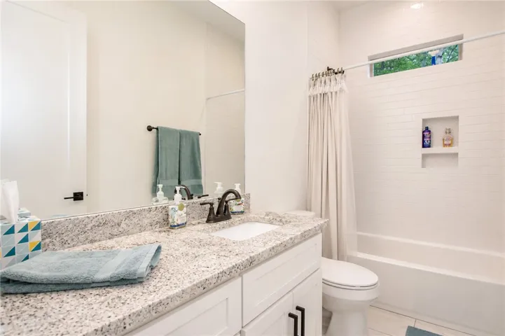 Marble-look counters and crisp white cabinetry create a serene atmosphere in this well-appointed bath.