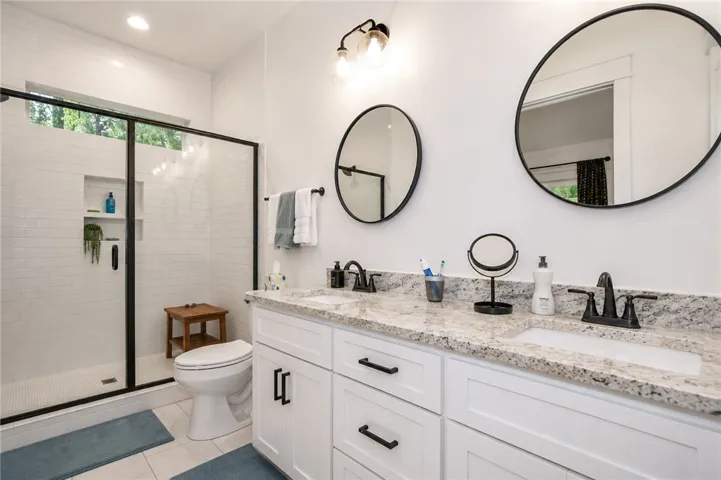 Luxurious bathroom offering a spacious shower, a dual vanity with granite counters, and recessed lighting.