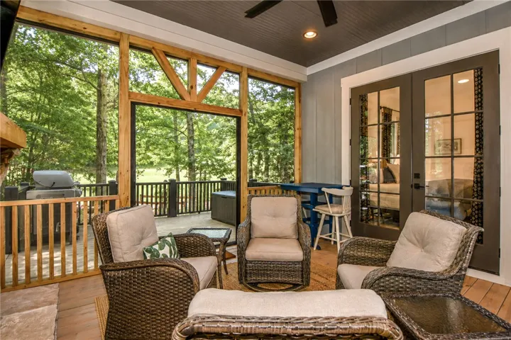 An inviting screened porch features ample seating and tranquil views of surrounding trees.