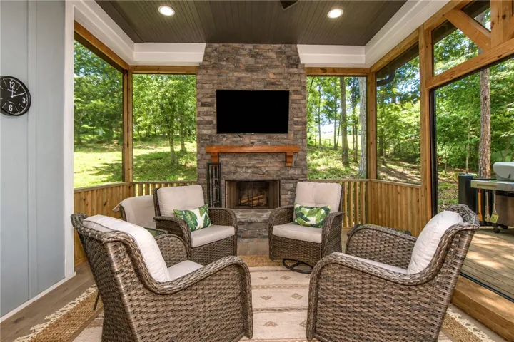 An inviting screened porch with a stone fireplace offers verdant views and ample space for relaxation.