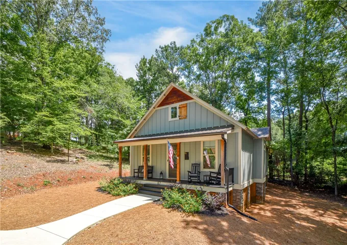 A charming cottage facade featuring a welcoming front porch with natural wood accents and sturdy stone foundation.