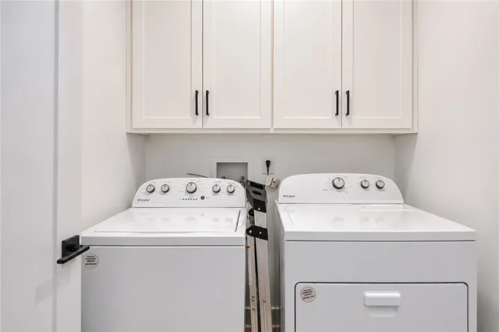 Functional laundry space featuring modern appliances and practical overhead storage.