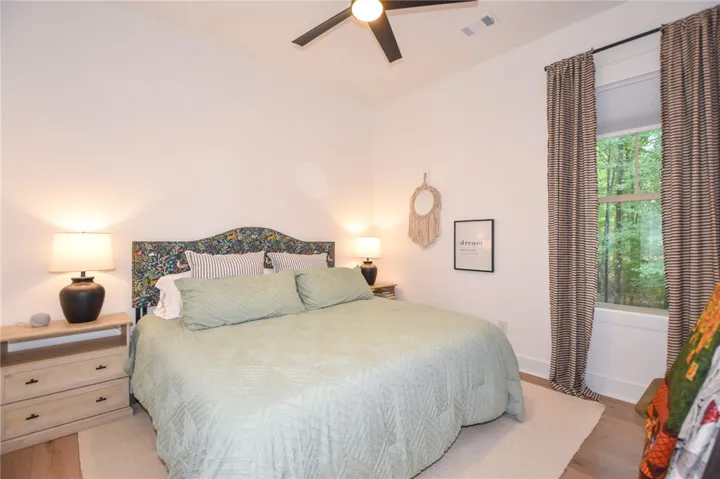 Well-lit sleeping quarters with a ceiling fan, light wood floors, and a private window view.