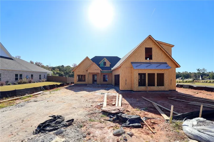 A new custom residence rises with classic gabled rooflines under a clear, sunlit sky.