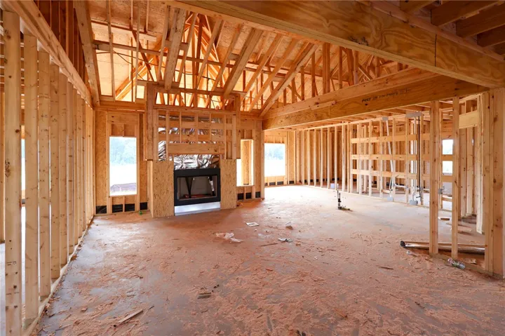 Dramatic vaulted framing and a central fireplace anchor this open-concept interior under construction.