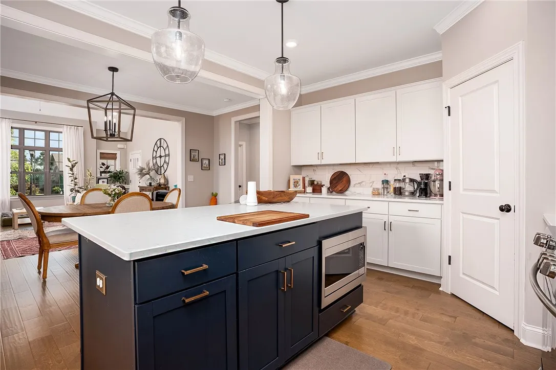 A well-appointed kitchen island with integrated microwave, showcasing abundant white cabinetry and rich hardwood flooring.