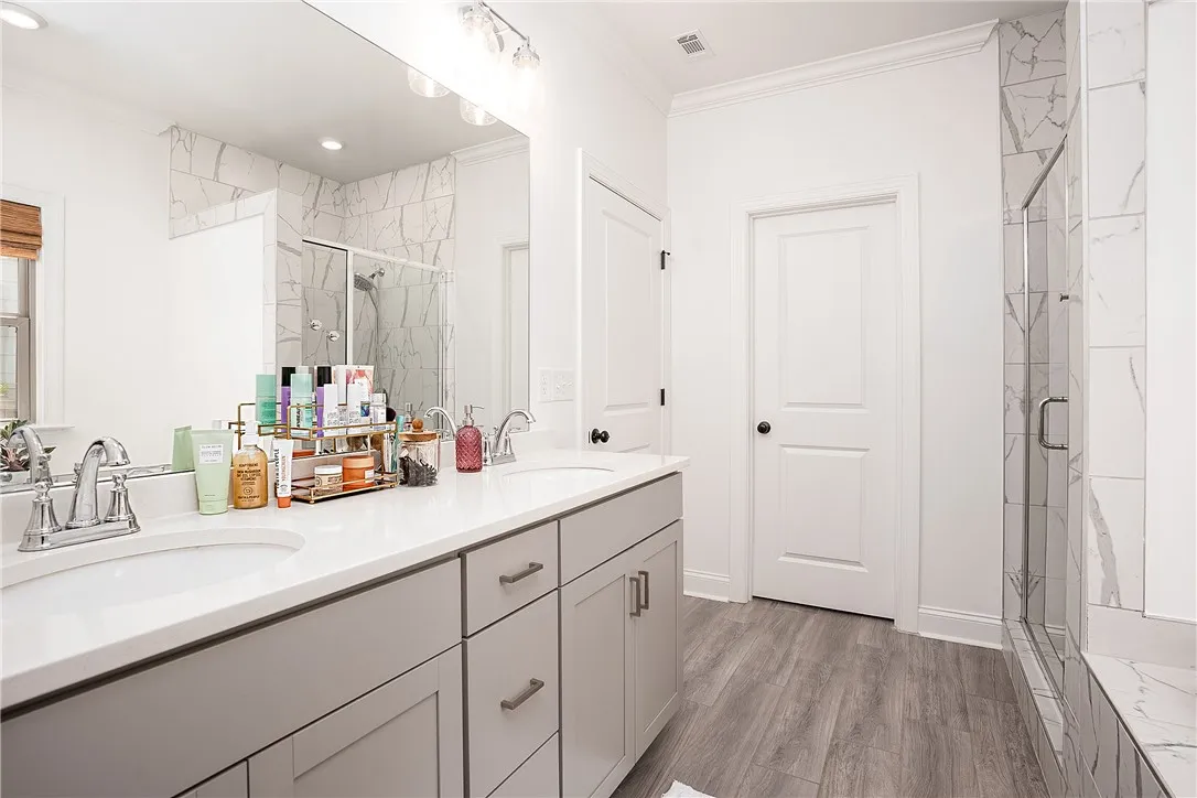Marble-tiled shower alongside a double vanity in this modern bath.