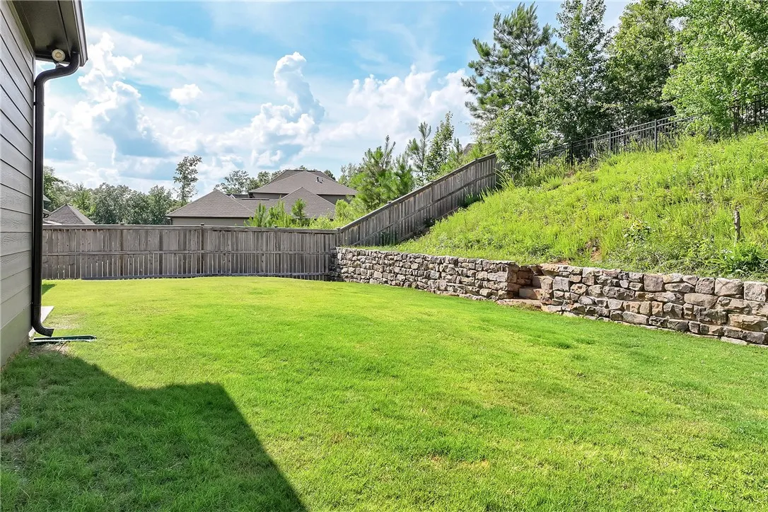 A tiered landscape unfolds, featuring a verdant lawn, sturdy privacy fencing, and an elegant stone retaining wall.