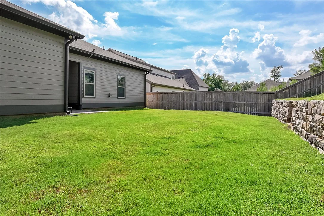 A spacious backyard awaits, complete with a stone retaining wall and a privacy fence.