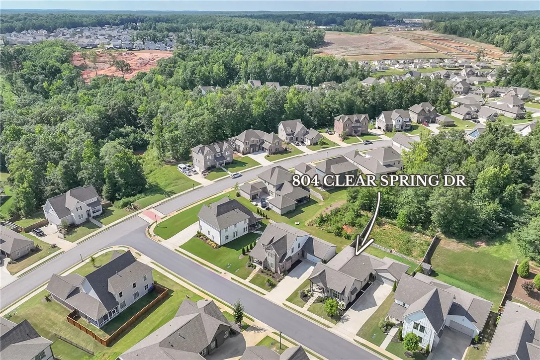 An aerial perspective reveals a well-planned community surrounded by lush, mature trees.