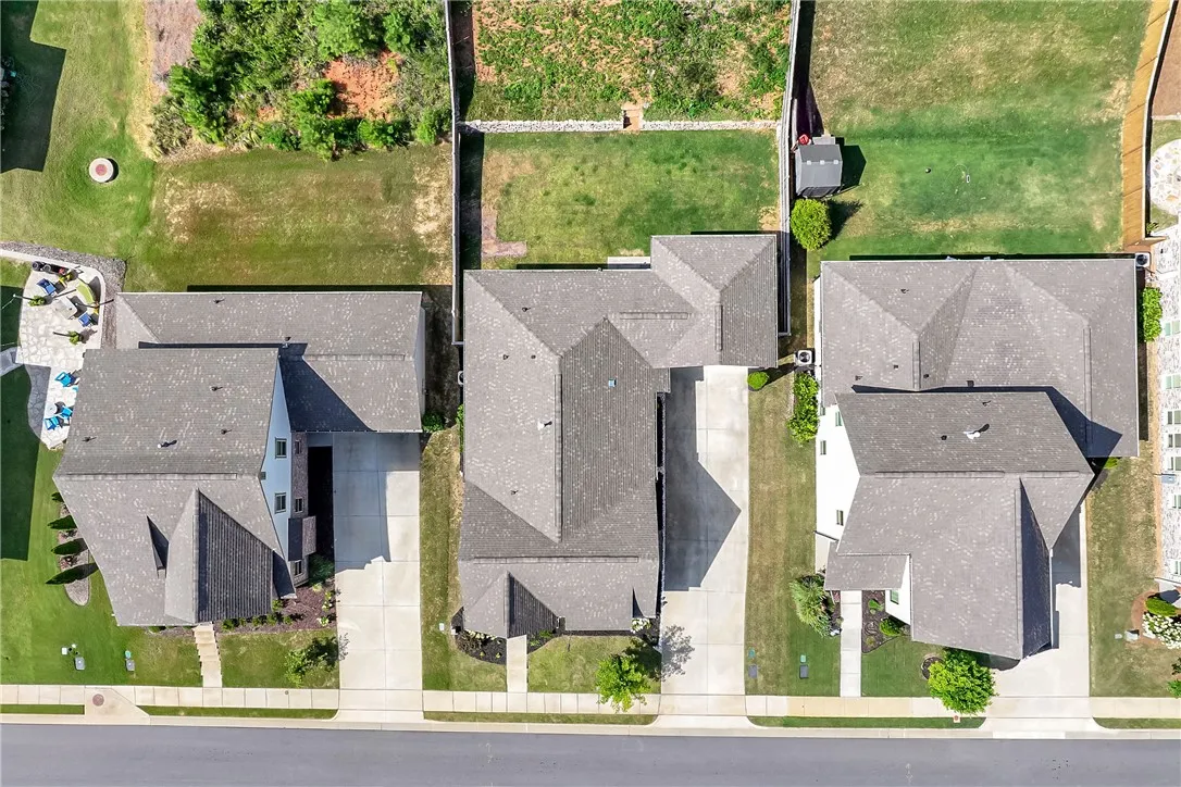 An aerial perspective reveals three residential properties with ample green space and paved driveways.