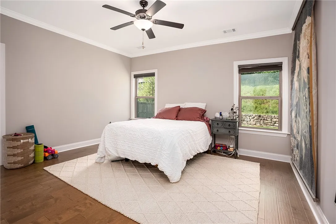 Well-lit sleeping quarters with rich hardwood flooring and bright window views.
