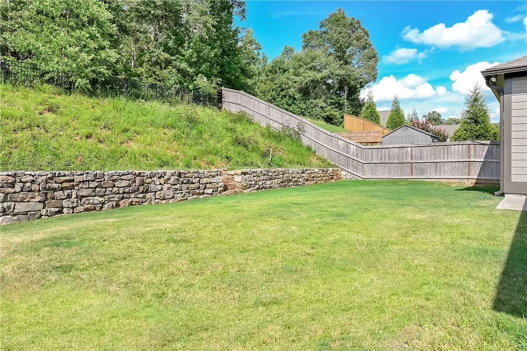 A well-maintained yard features a stone retaining wall and a privacy fence.