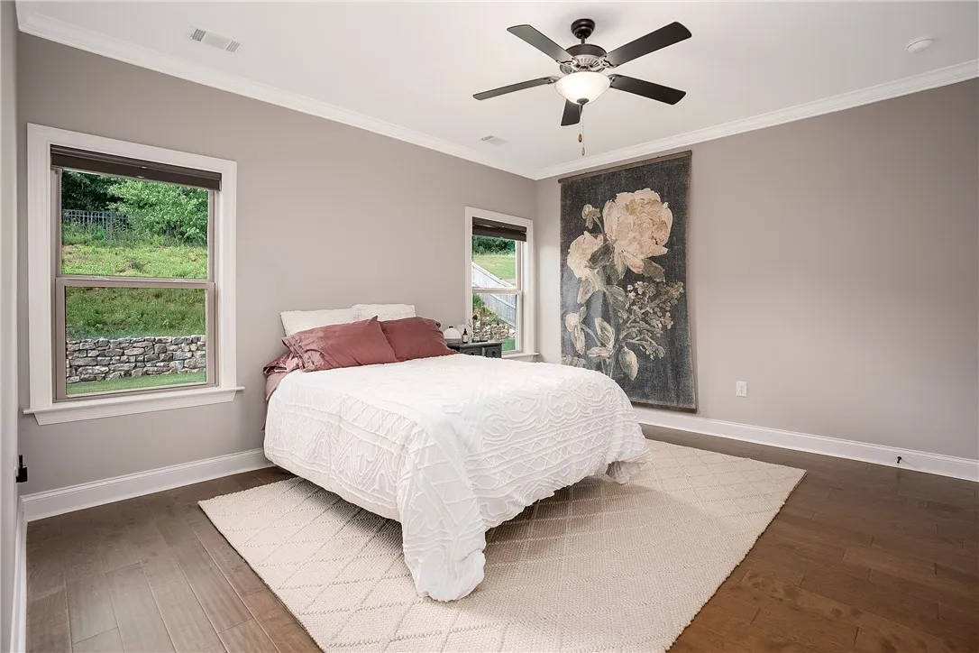 Hardwood floors and a serene landscape view create a comfortable and private bedroom.