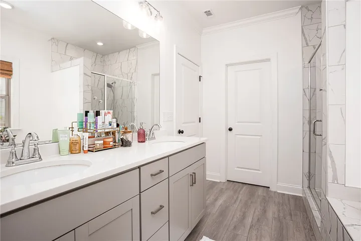 Marble-tiled shower alongside a double vanity in this modern bath.