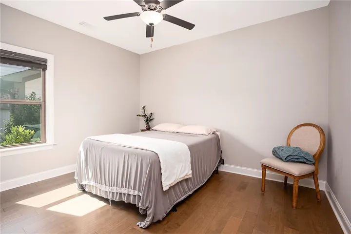 Hardwood floors and a window offer warmth and natural illumination in this comfortable bedroom.