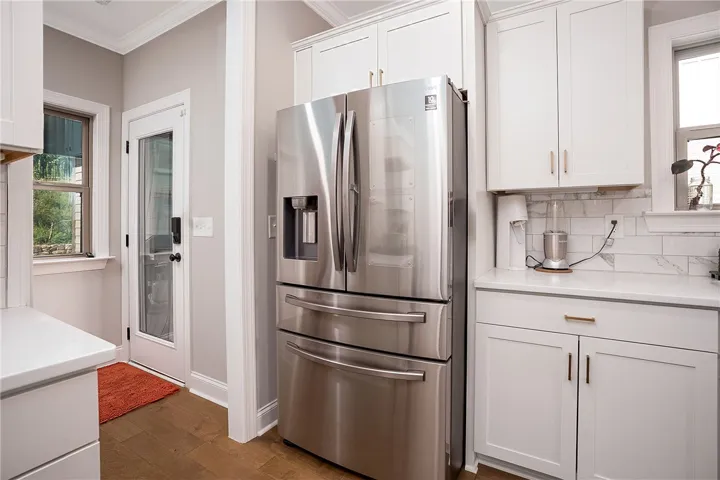 A well-equipped kitchen features a stainless steel refrigerator and ample white cabinetry, ideal for culinary endeavors.