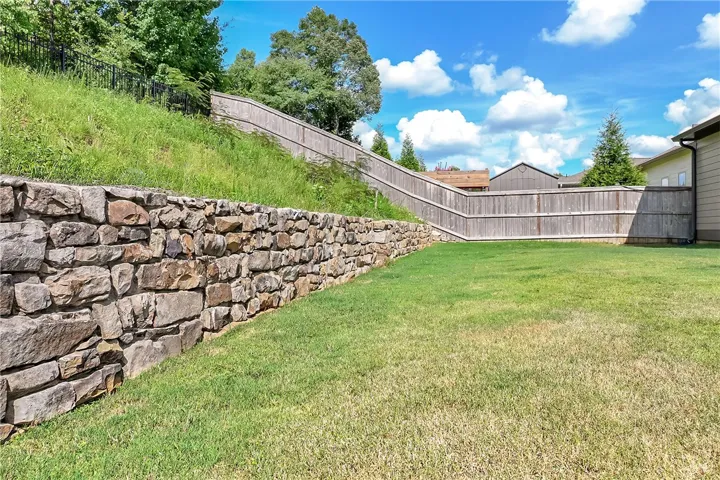 A well-maintained yard provides ample space for recreation, complemented by natural stone and wood privacy fencing.