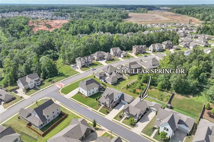 An aerial perspective reveals a well-planned community surrounded by lush, mature trees.