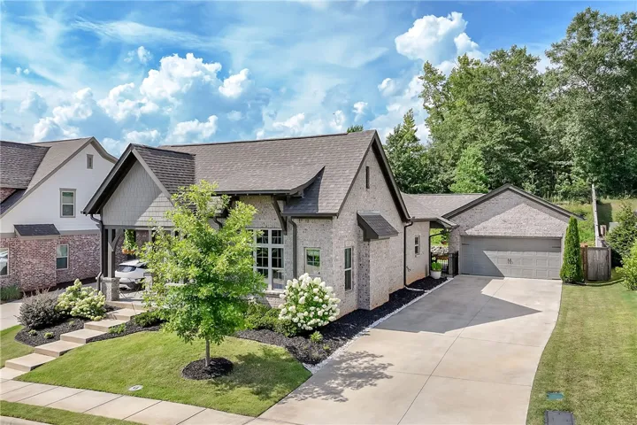 A striking gray brick home features a gabled roofline and an attached garage with a paved driveway.