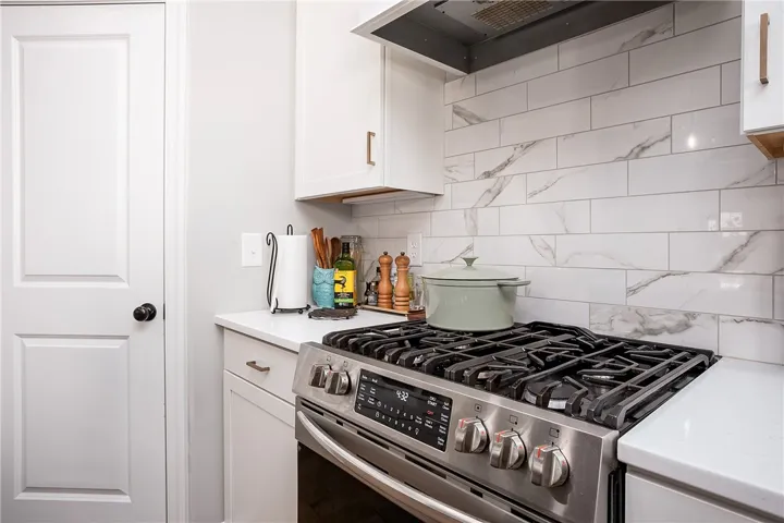 Modern kitchen equipped with a stainless steel gas range and a sleek subway tile backsplash.