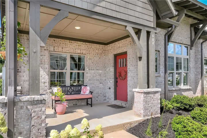 A welcoming front porch, adorned with a vibrant red entry door, invites you into this charming residence.