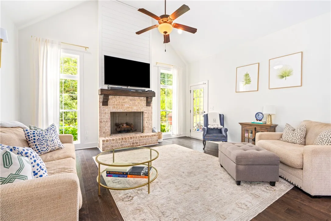 A spacious living room features soaring vaulted ceilings, rich hardwood flooring, and a gas fireplace