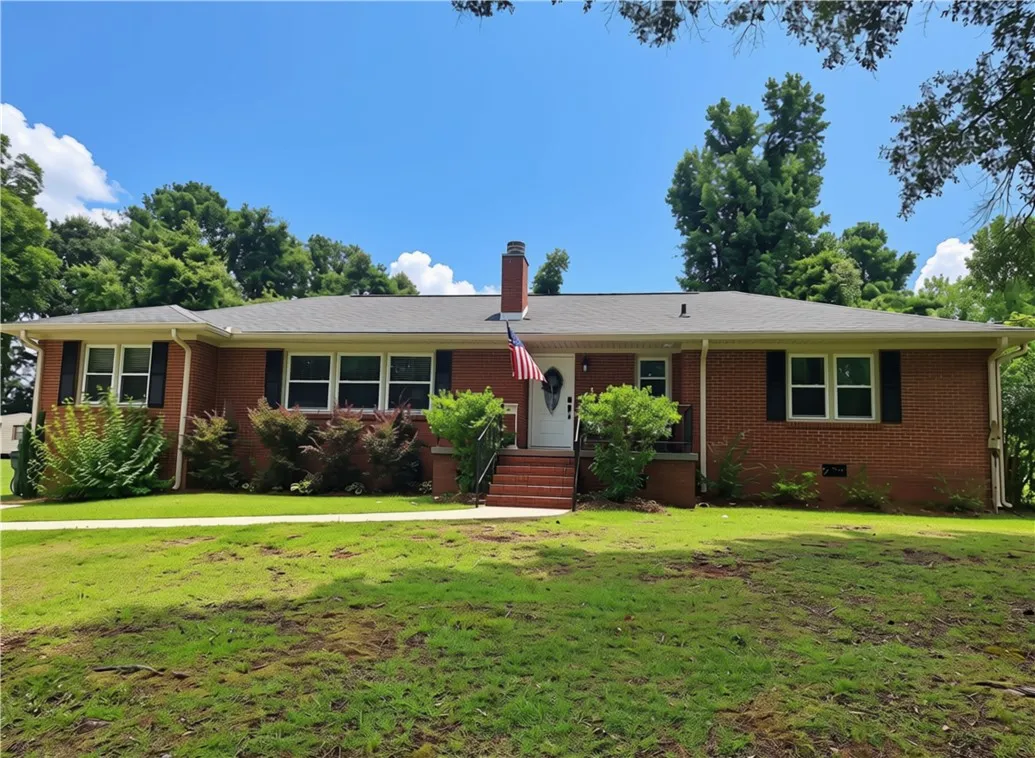 A classic brick ranch home welcomes with a neatly manicured lawn and mature landscaping.