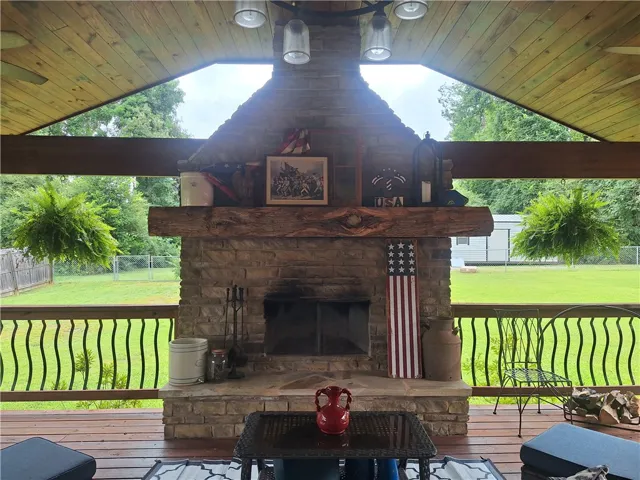 A stone fireplace provides a focal point for this inviting outdoor patio with wood planking and overhead lighting.