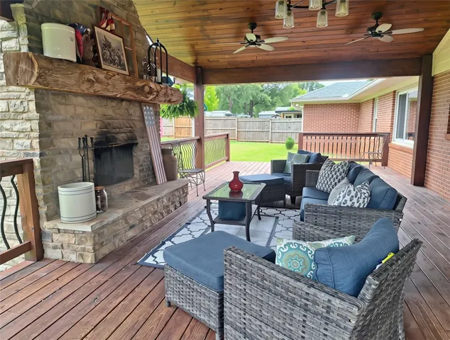 An inviting outdoor living space features a stone fireplace and a wood-beamed ceiling.