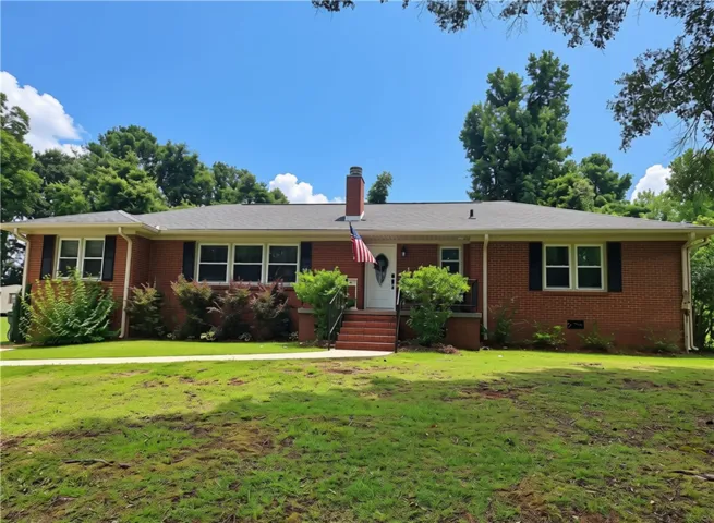 A classic brick ranch home welcomes with a neatly manicured lawn and mature landscaping.